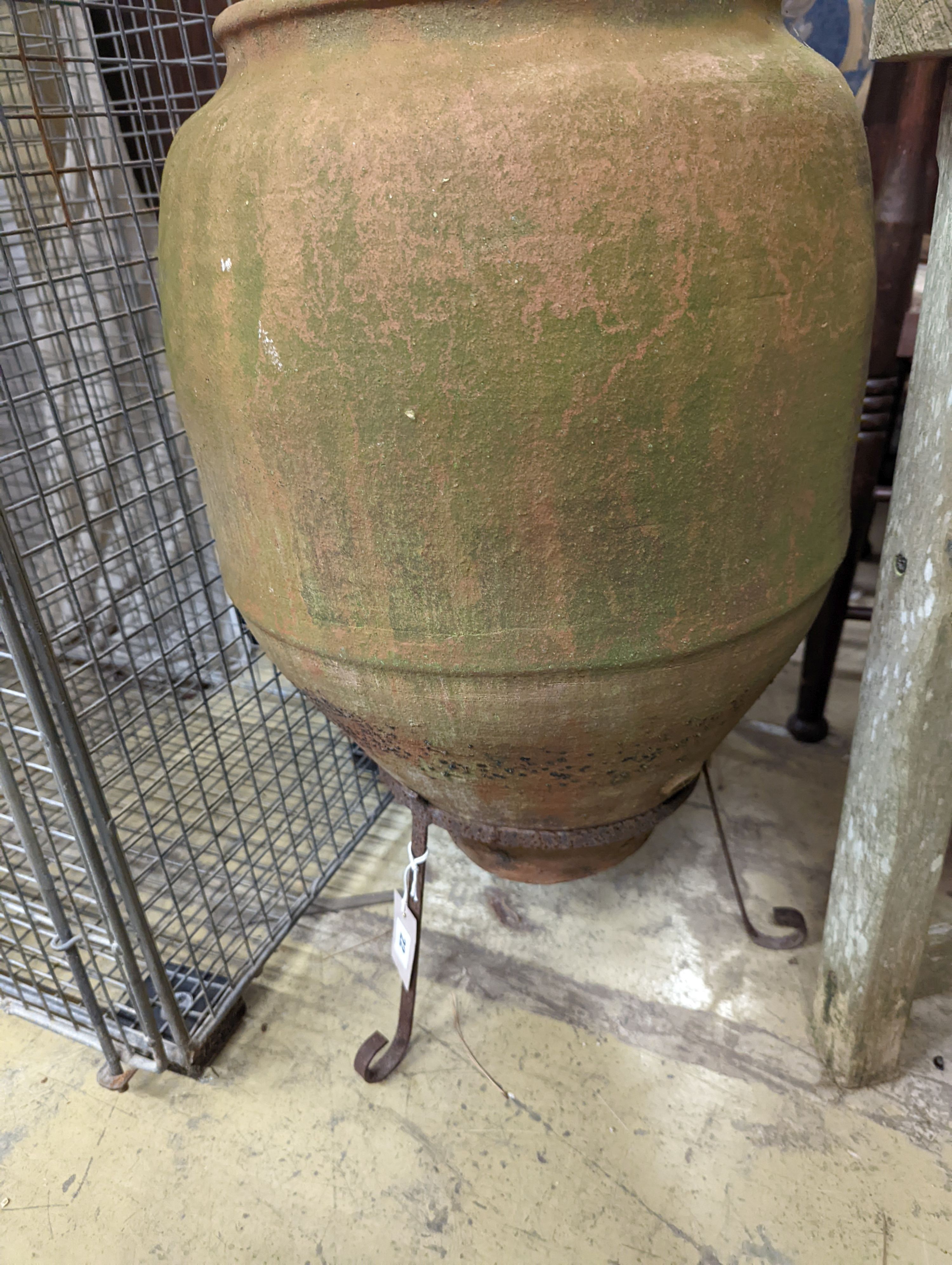 A terracotta garden urn on wrought iron stand. W-38cm, D-38cm, H-68cm.